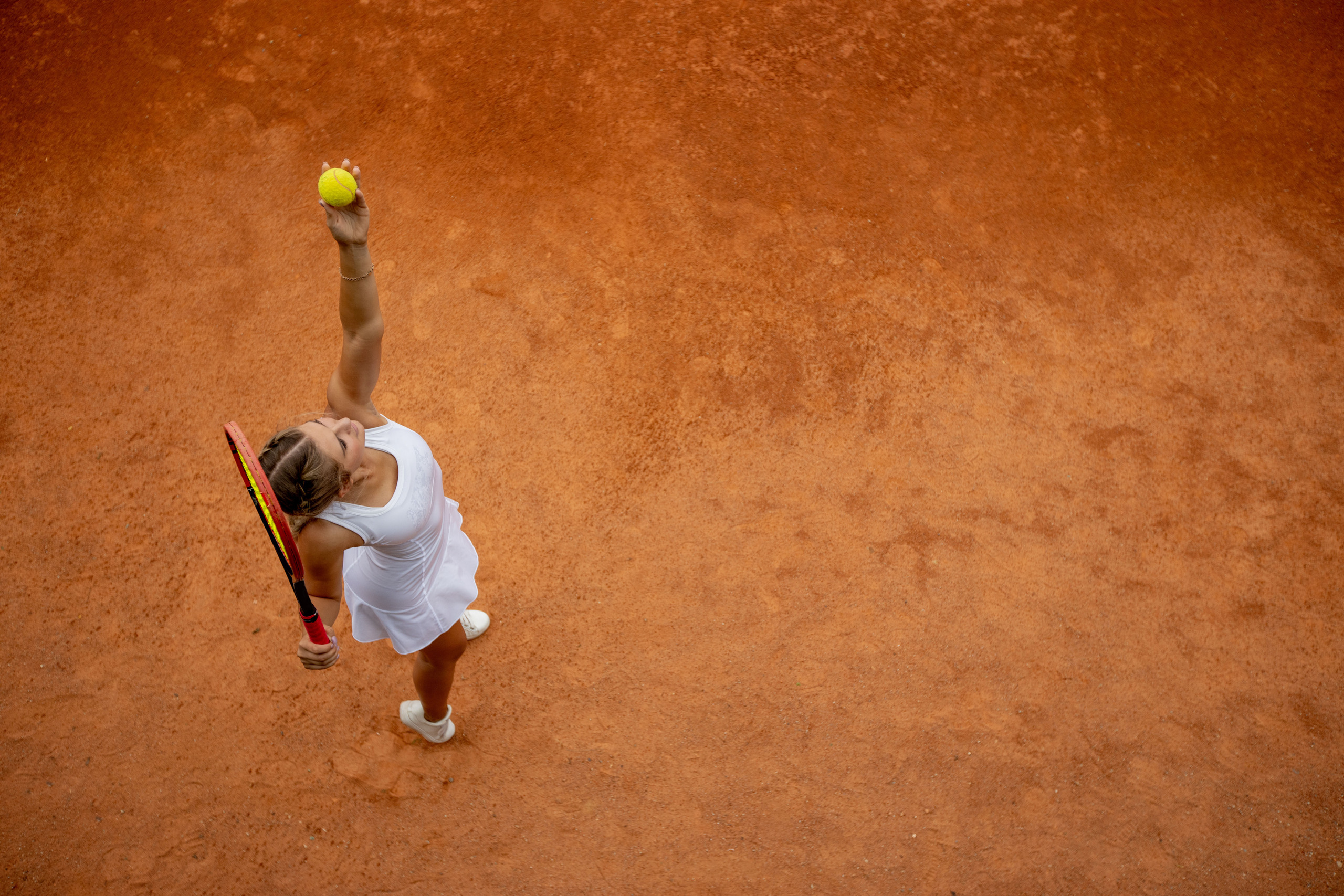 Tennis player in white sportswear preparing to serve tennis ball, training before match.